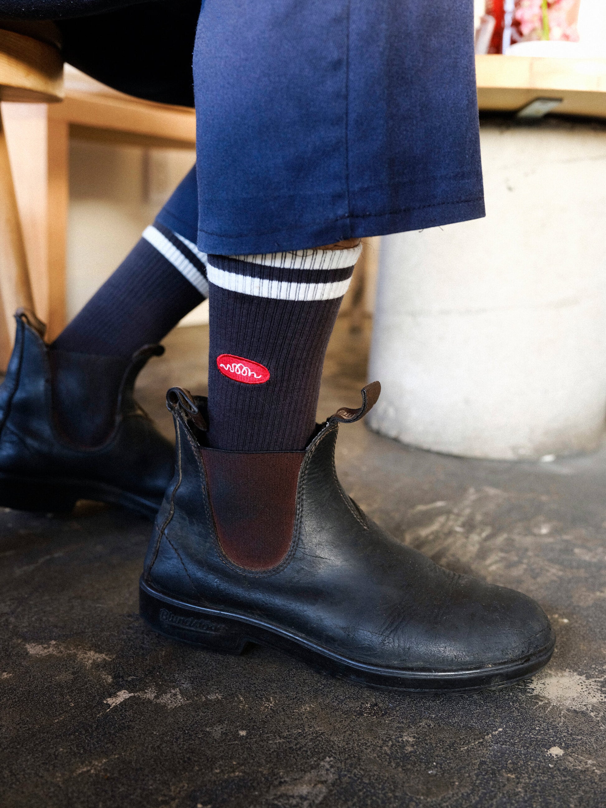 A person wearing black socks with white stripes and orange woon logo