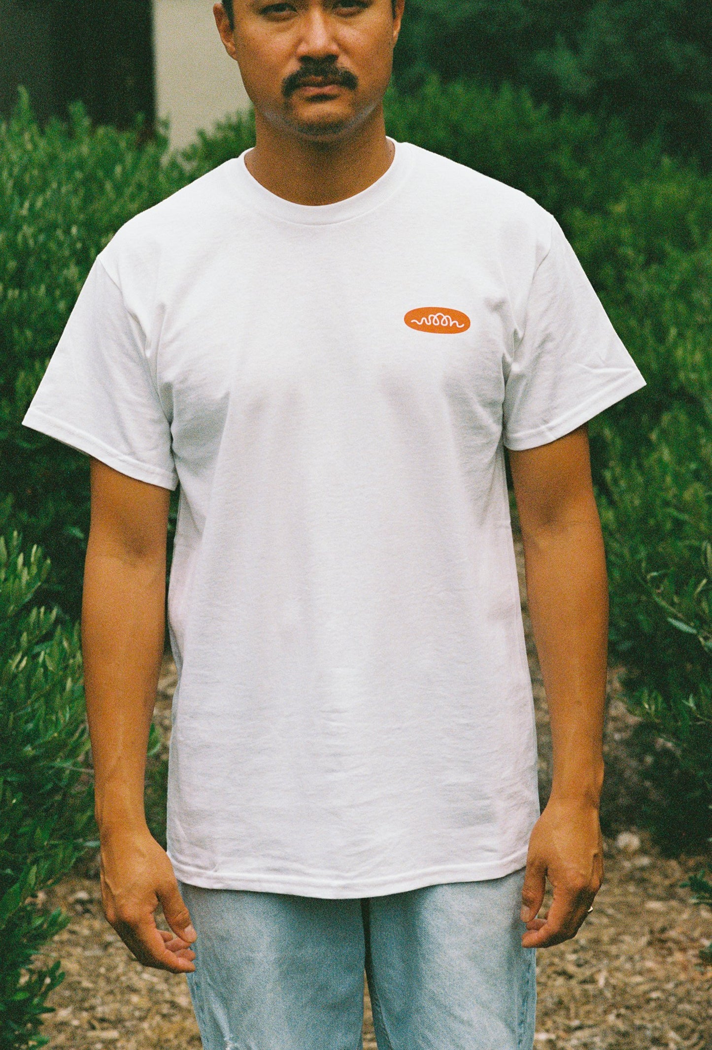 A person wearing a white tee shirt with Woon logo in orange
