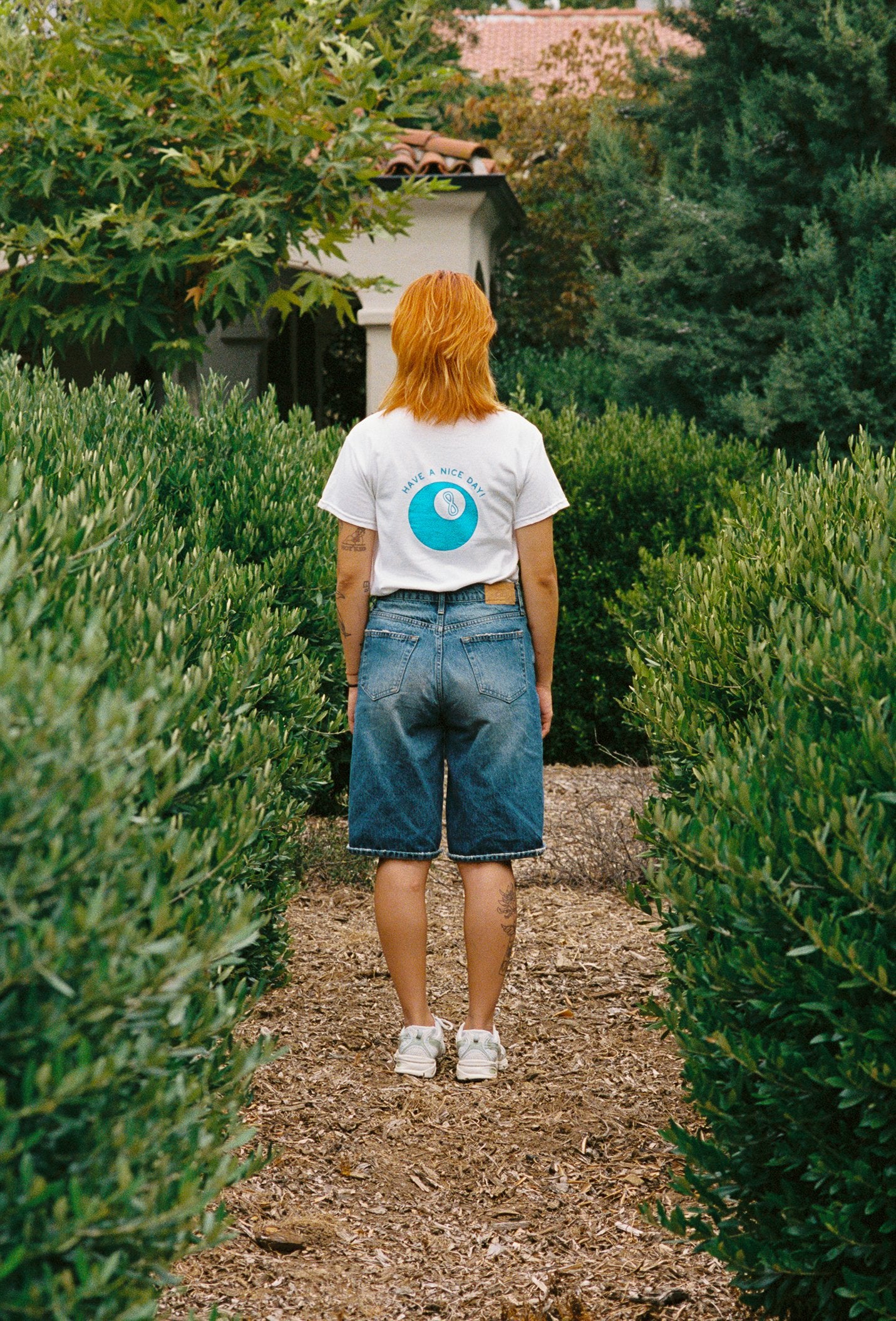 A person with their back turned toward the camera and a white tee shirt on with a lucky 8 ball