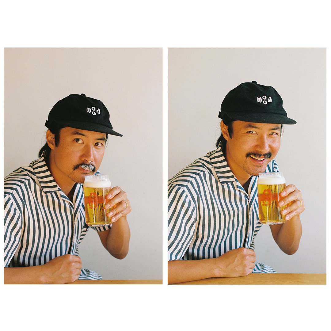 A person drinking a beer out of a glass with a woon logo
