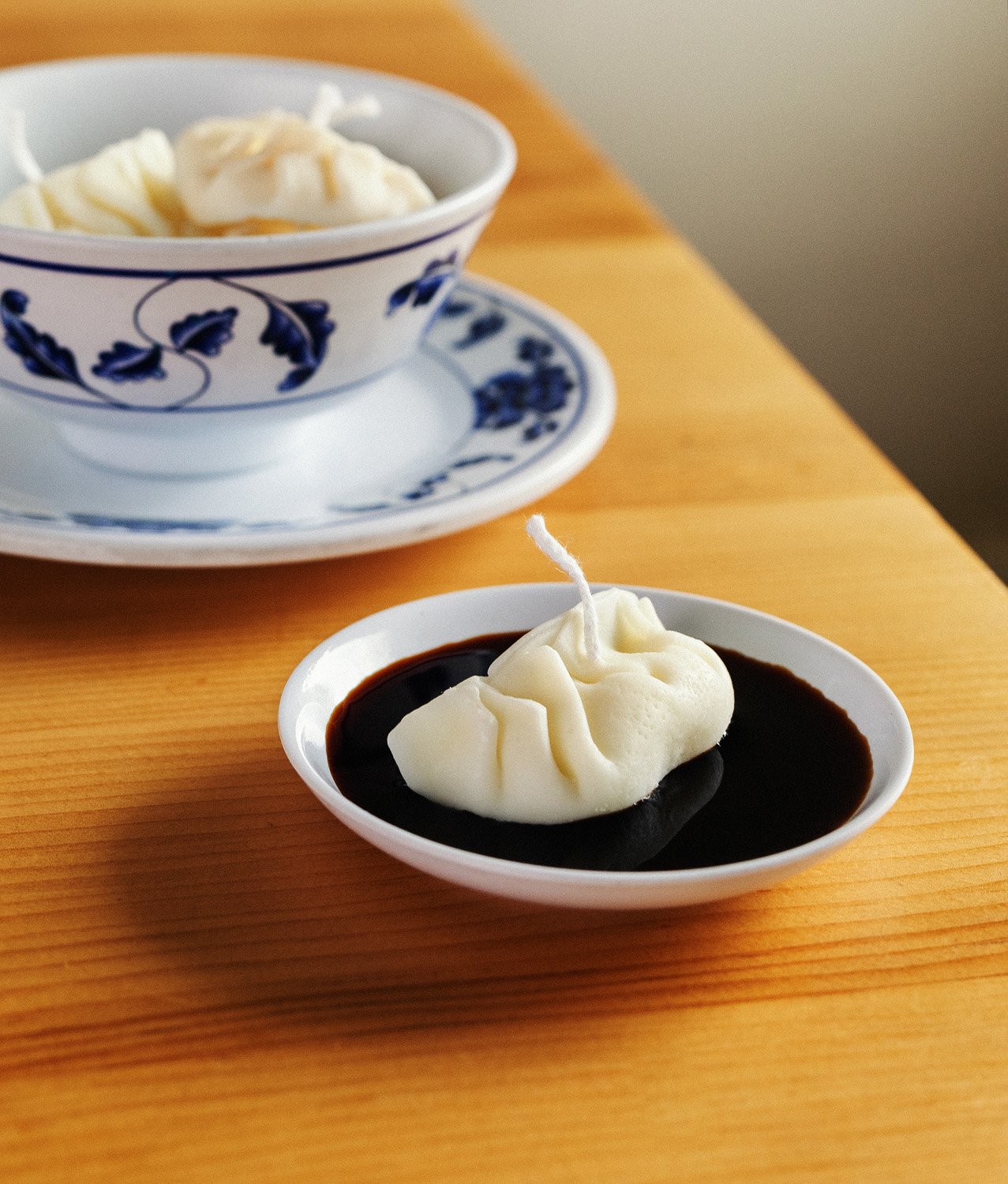 A dumpling candle floating in a bowl of soy sauce
