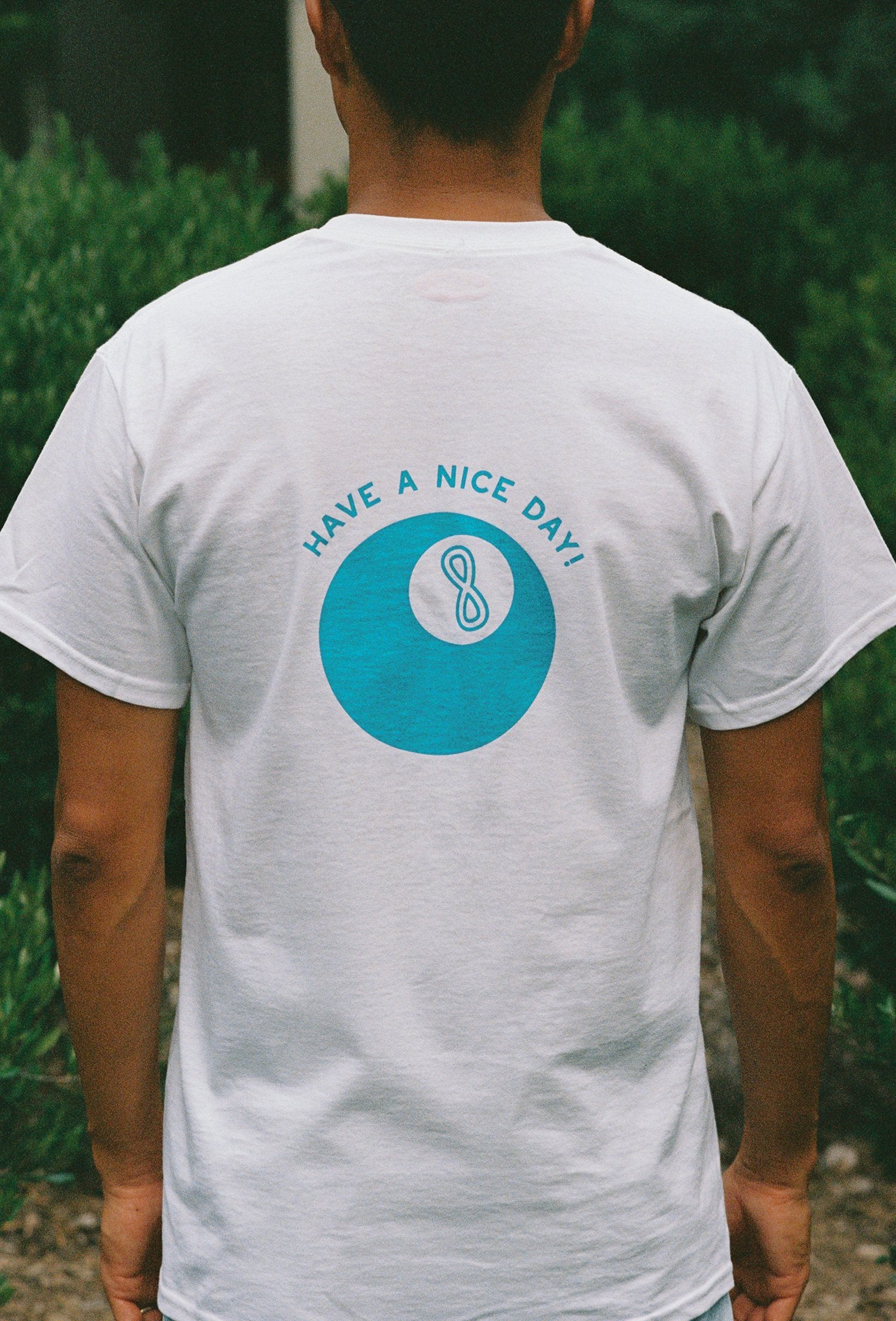 Close up of a man wearing a white t shirt with a lucky 8 ball on it
