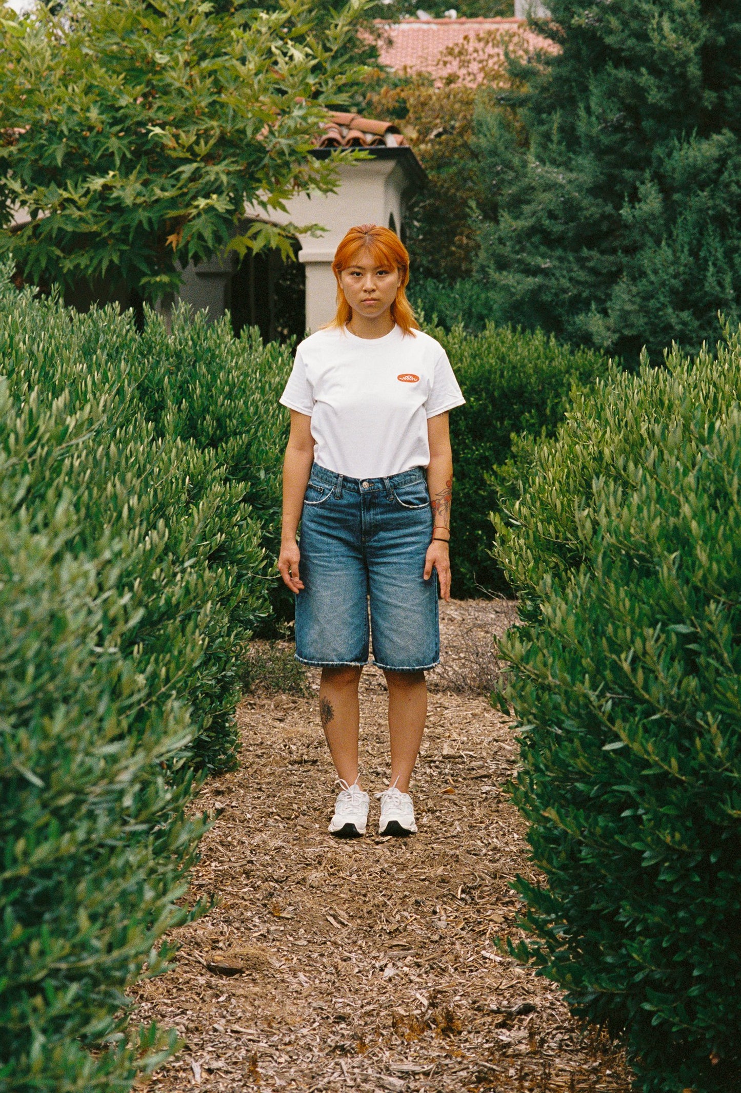A person standing in bushes with a white t shirt on with a Woon logo