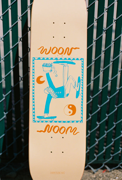 Skateboard with woon logo and person skating and eating noodles on it. 
